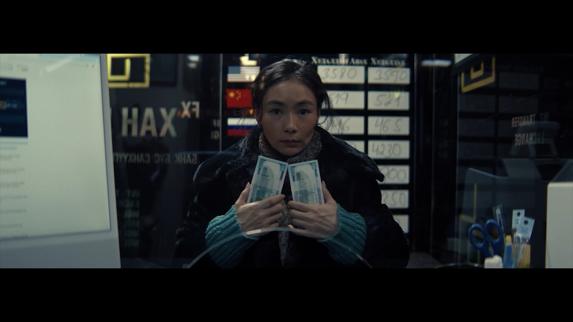 Saraa at a currency-exchange window, holding two bricks of US dollars